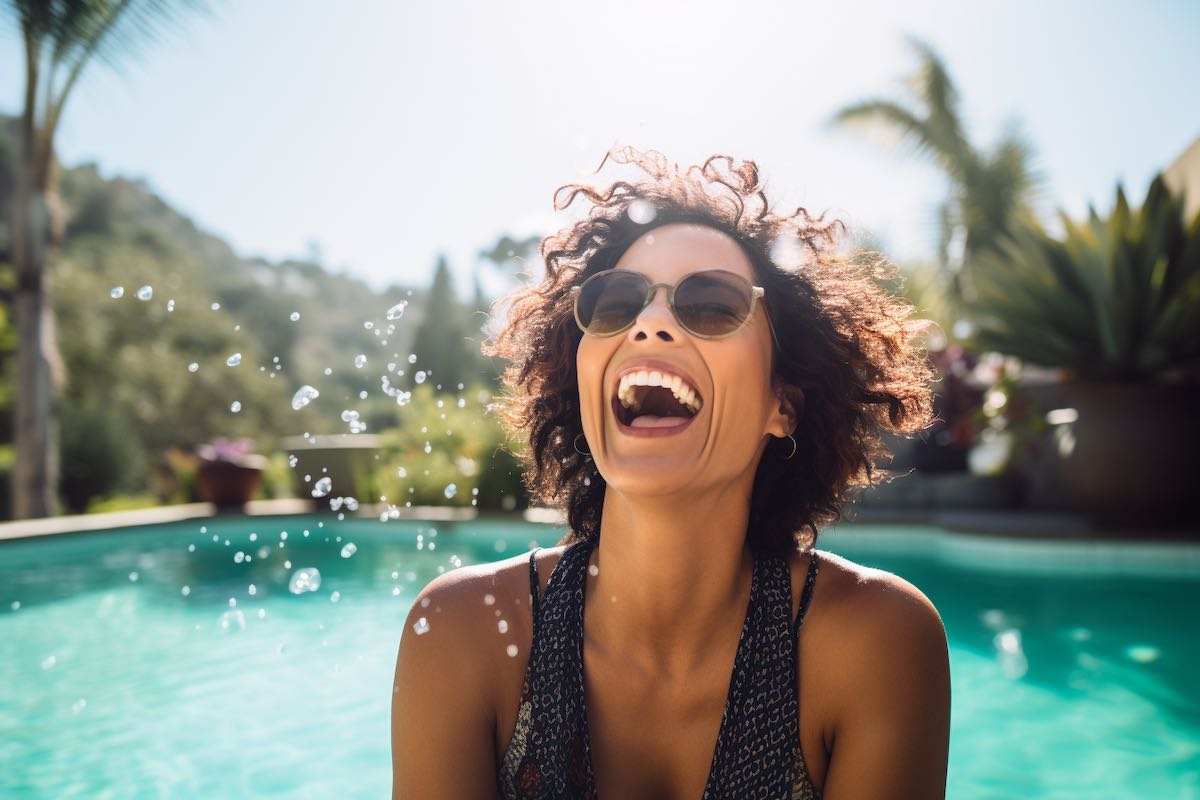 A joyful woman, mid-laugh, iin a  sparkling pool, not worried about her heath "down there"